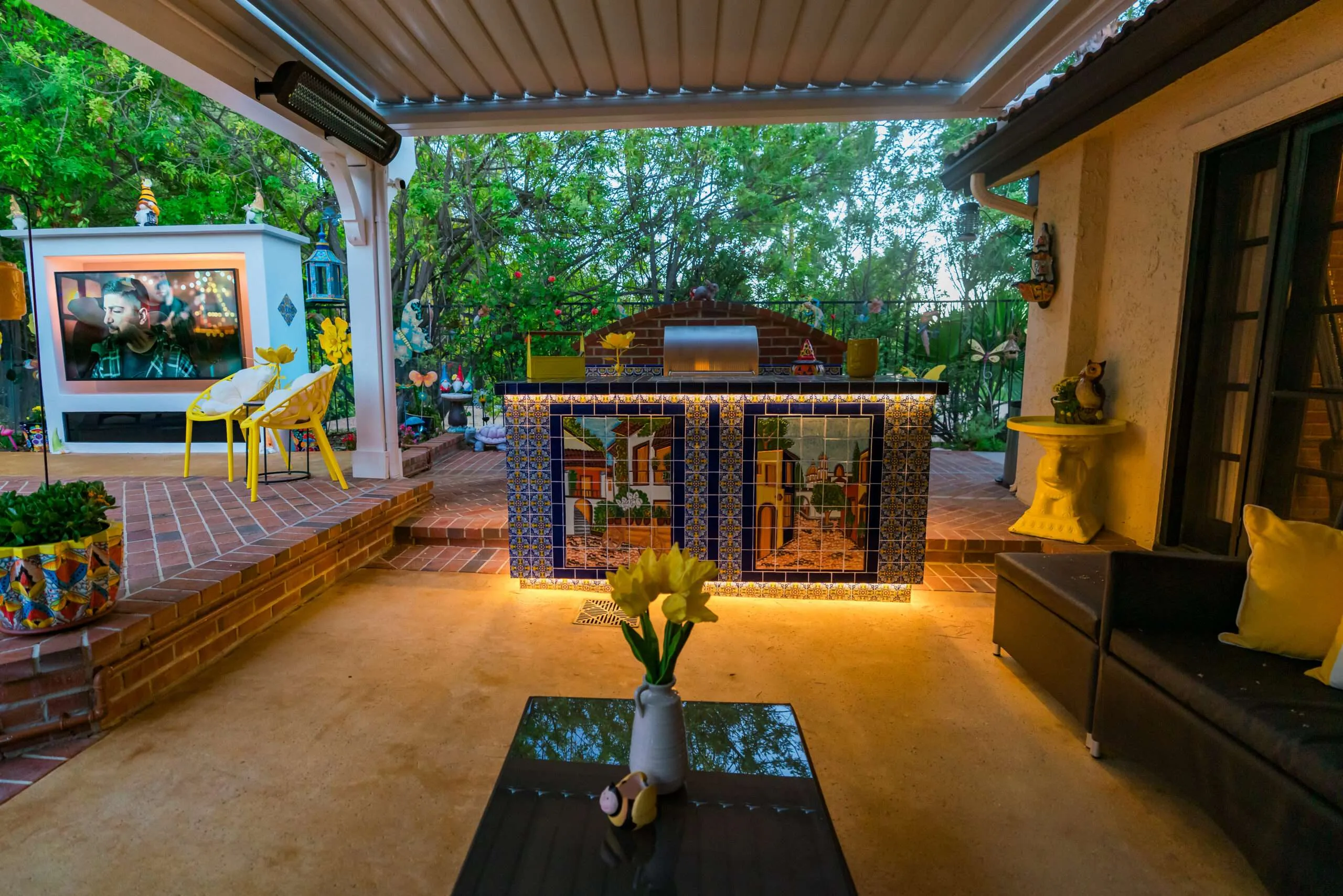 Custom outdoor BBQ island with Spanish-style decorative tile, louvered motorized patio cover, integrated lighting, and outdoor living space in Encino, CA