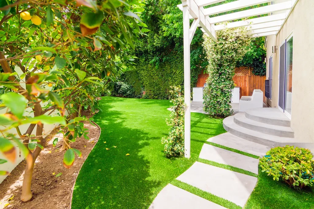 Artificial turf lawn installation with concrete stepping stone pathway and pergola structure designed by Lush Gardens Inc.