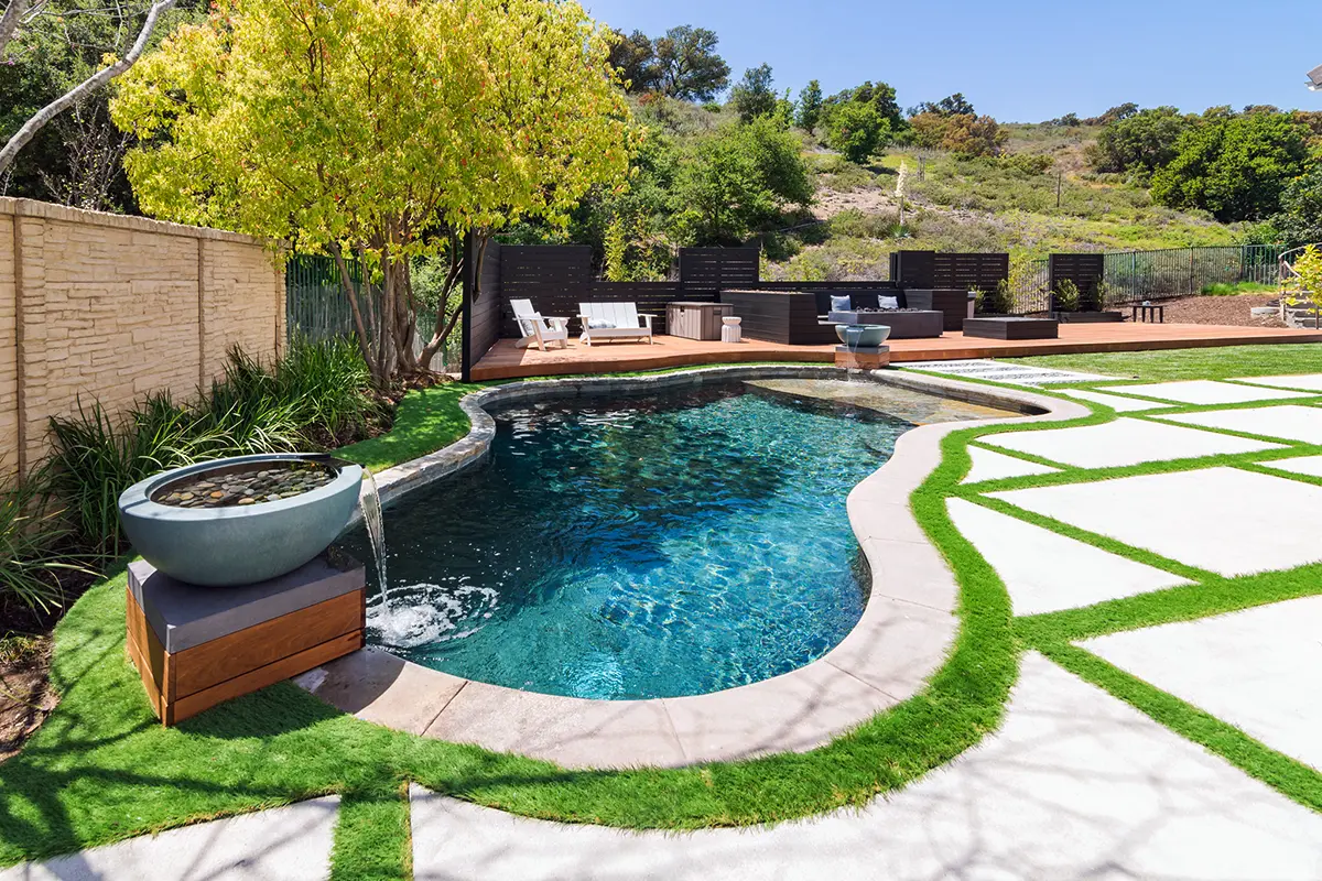 Modern backyard landscape and softscape design with custom pool, concrete walkways, and integrated planting designed and installed by Lush Gardens Inc.