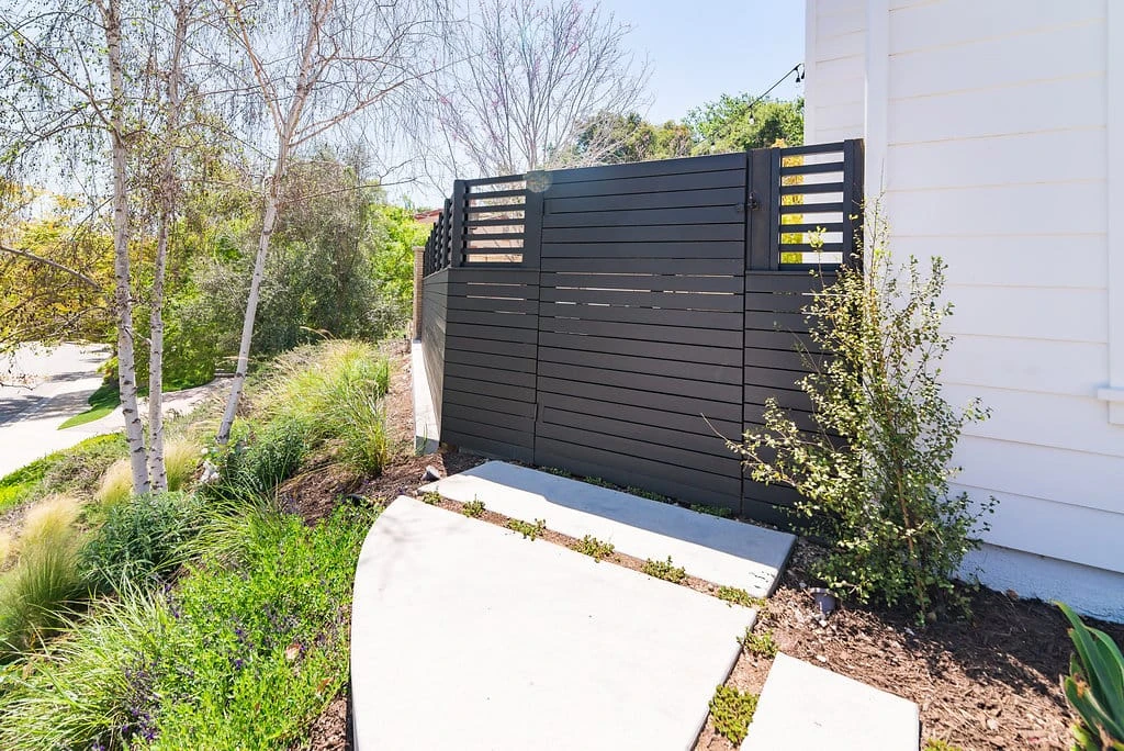 Custom redwood fence and gate with horizontal slat design and concrete pathway in Westlake Village, CA