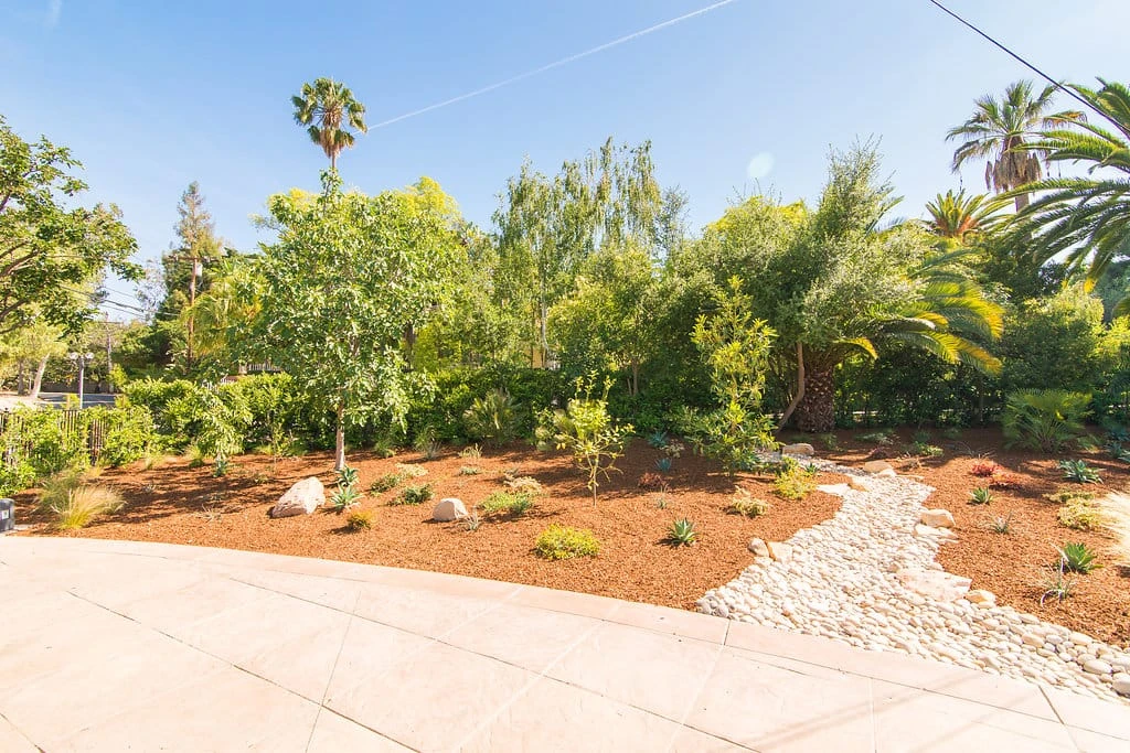 Front yard dry creek bed with drought tolerant landscaping and concrete walkway by Lush Gardens Inc in Encino CA